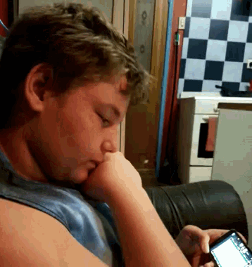 a young boy is sitting on a couch looking at his phone