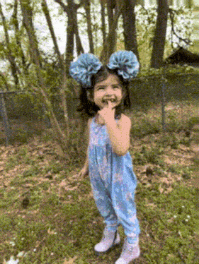 a little girl wearing blue overalls and a blue bow on her head