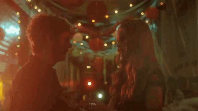 a man and a woman are dancing together in a dark room with lights .