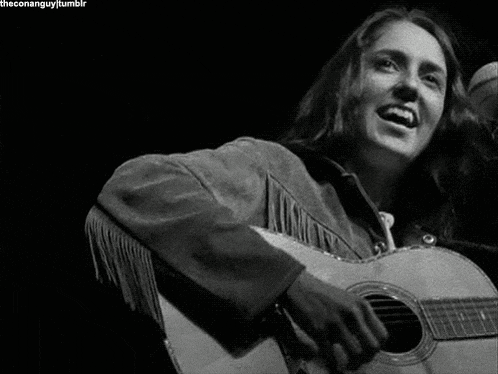 a black and white photo of a woman playing a guitar and smiling .