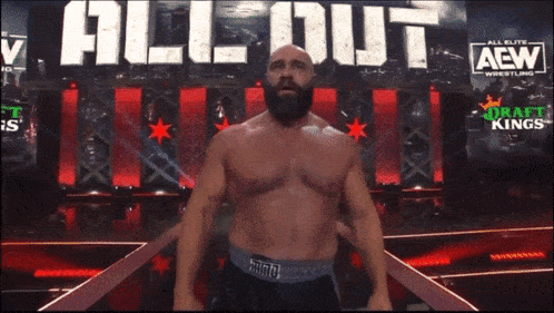 a wrestler is standing in front of a sign that says all elite wrestling