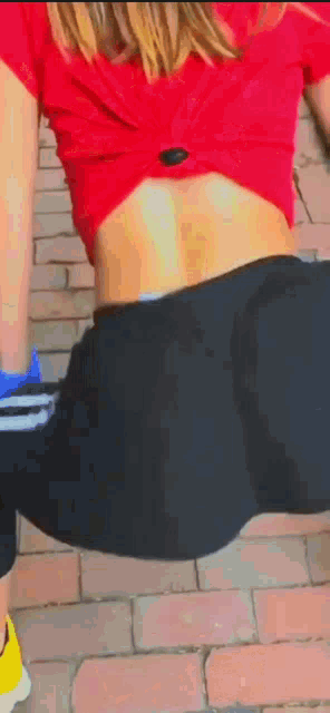 a woman in a red top and black leggings is doing a squat