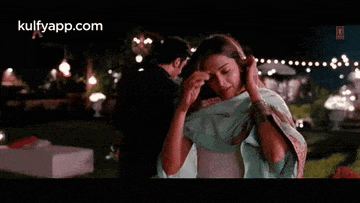 a woman in a blue sari is dancing in a park at night .