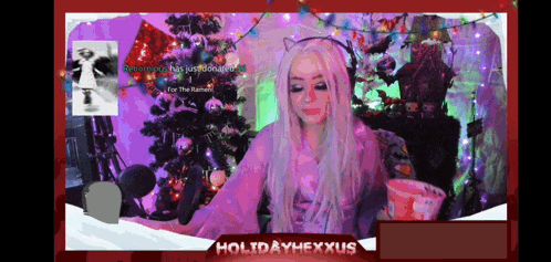a girl is sitting in front of a christmas tree with the words holidayhexxus on the bottom right