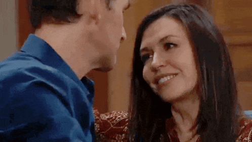 a man and a woman are looking at each other and smiling while sitting next to each other .