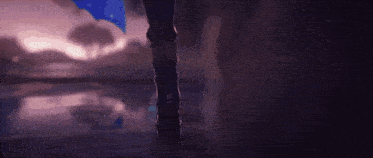 a person is holding a sword in a dark room with a blue light behind them .