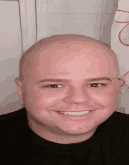 a smiling bald man with a black shirt on