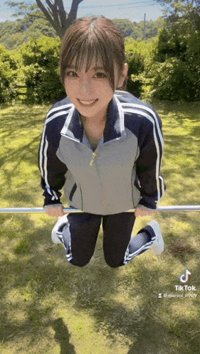 a young woman is kneeling down on the ground holding a bar .