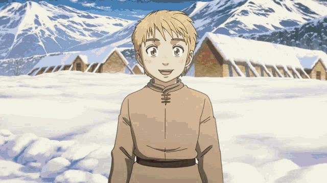 a young boy stands in front of a snowy mountain