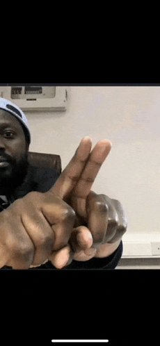 a man in a hat is making a peace sign with his hands .