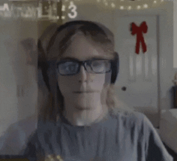 a man wearing headphones and glasses is sitting in front of a computer screen .