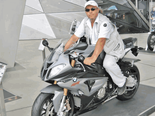 a man sitting on a bmw motorcycle wearing a nike hat