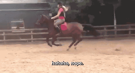a woman is riding a horse in a fenced in area and laughing .