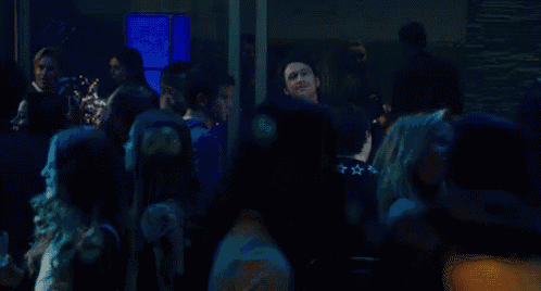 a man in a plaid shirt is dancing in a crowd of people