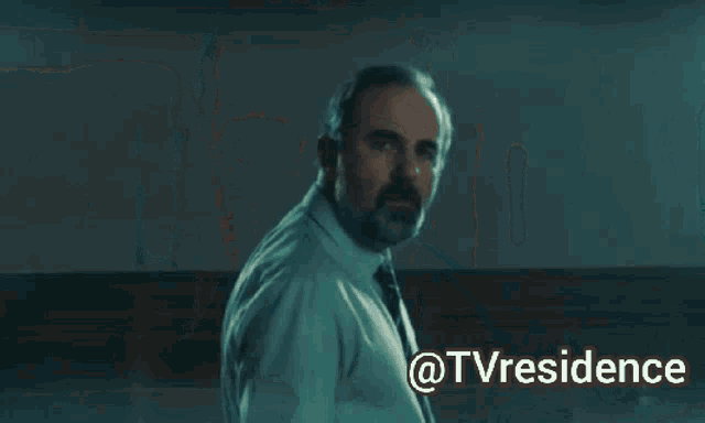 a man in a suit and tie is looking down with the words @tvresidence above him