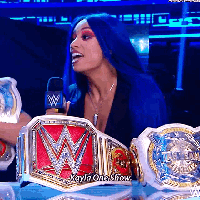 a woman with blue hair is holding a wwe championship belt