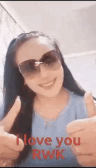 a woman wearing sunglasses is smiling and giving a thumbs up sign .