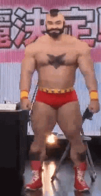 a man with a beard and a tattoo on his chest is standing in front of a sign that says ' a '