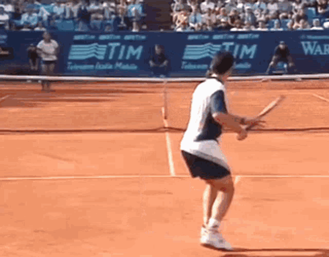 a tennis player is swinging a tennis racket on a court with a tim advertisement behind him
