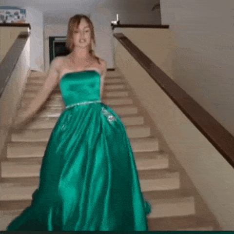 a woman in a green strapless dress is walking down stairs