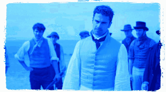 a man in a white vest and tie stands in front of a group of men
