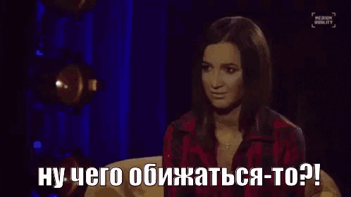 a woman in a plaid shirt is sitting on a couch and talking in russian .