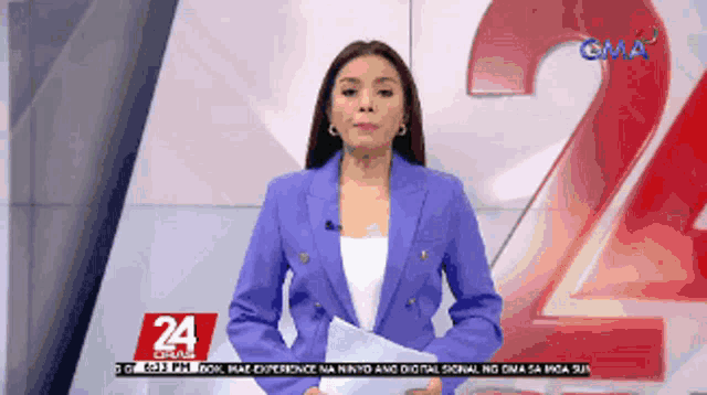 a woman in a blue jacket stands in front of a large number 24