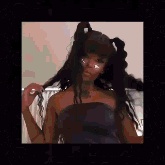 a woman with pigtails and rhinestones in her eyes is wearing a black strapless top .