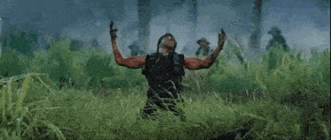 a man standing in a field with his arms outstretched and a helicopter in the background .