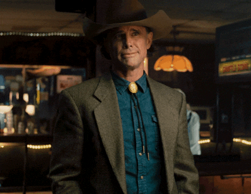 a man wearing a cowboy hat and a jacket giving the middle finger