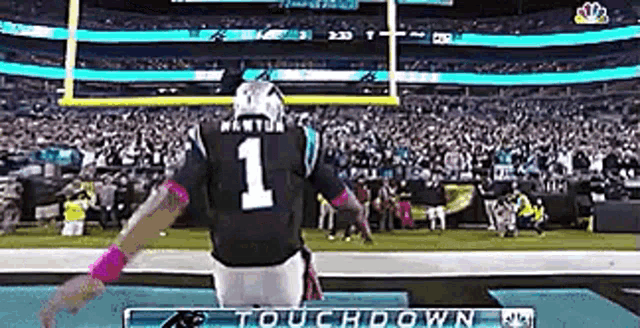 a football player wearing a number 1 jersey is standing on the sidelines of a football field .