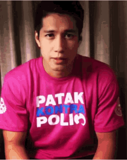 a man wearing a pink t-shirt that says patak kontra polio