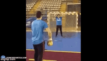 a man in a blue shirt is standing in front of a soccer net