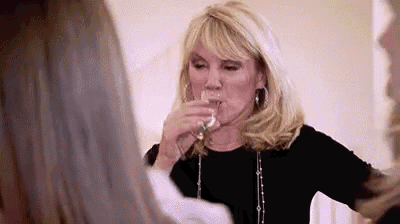 a woman is drinking a glass of wine while another woman watches .