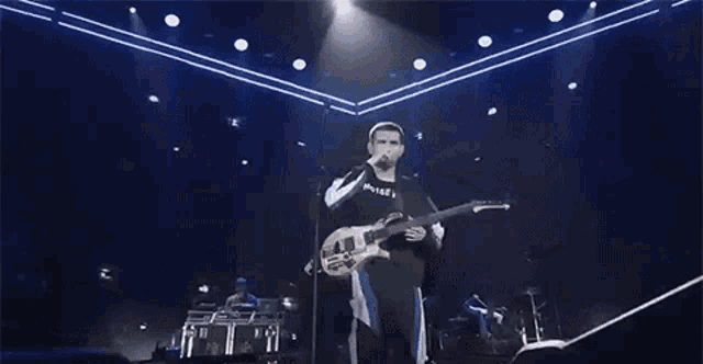 a man is playing a guitar on a stage in front of a crowd .