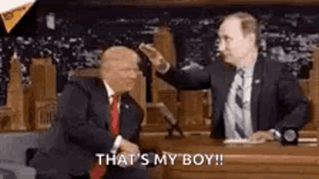a man in a suit and tie is shaking hands with another man .