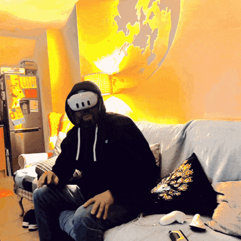 a man wearing a mask sits on a couch in front of a map of the world