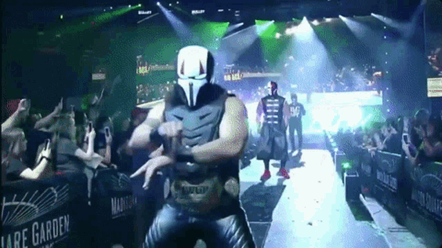 a man in a mask is walking on a stage with a sign that says lare garden in the background