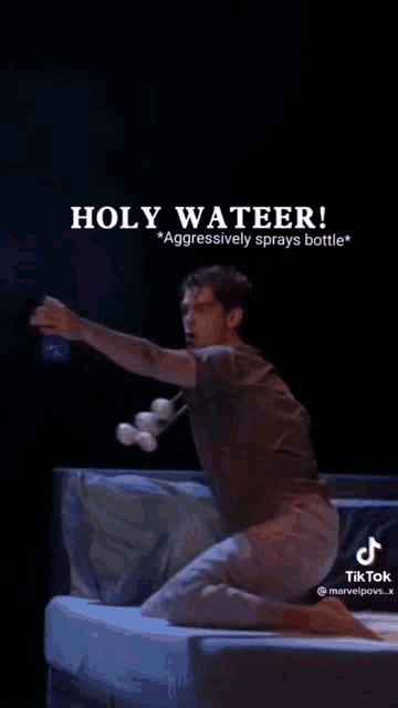 a man is kneeling on a bed holding a bottle of water and a bottle of marshmallows .