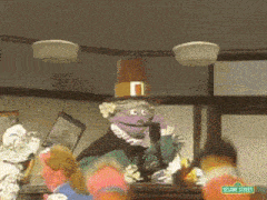 a sesame street character wearing a pilgrim hat talks on a cell phone