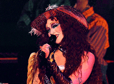 a woman singing into a microphone with a cowboy hat on