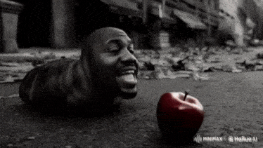a black and white photo of a man laying on the ground next to a red apple that says minimax on it