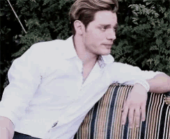 a man in a white shirt is leaning on a striped chair