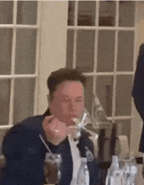 a man is sitting at a table with a spoon in his mouth .