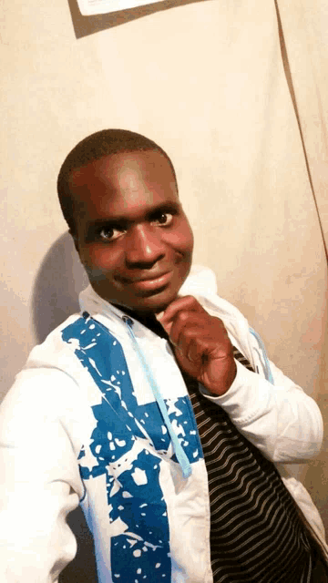 a man wearing a white jacket with blue spots on the sleeves is smiling