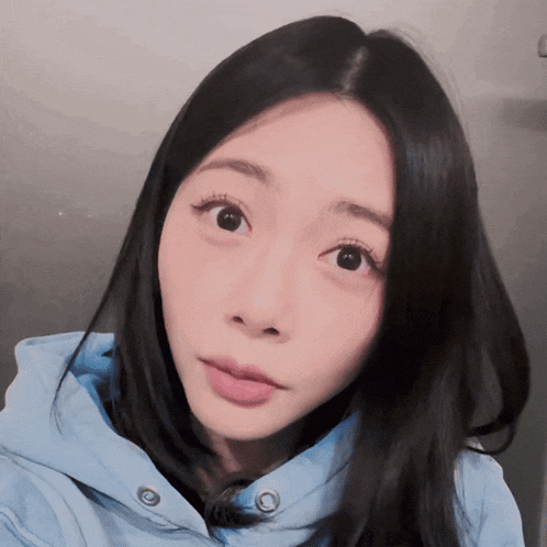 a woman with long black hair wearing a blue jacket