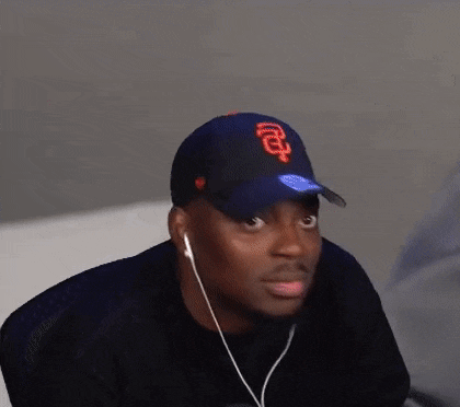a man wearing a baseball cap and headphones is making a surprised face .