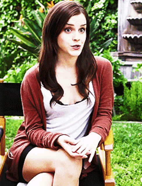 a woman in a red cardigan sits in a chair