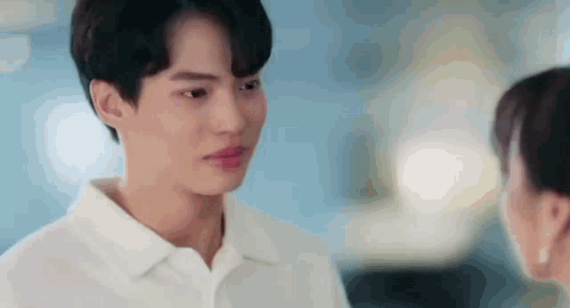 a man and a woman are looking at each other . the man is wearing a white shirt .
