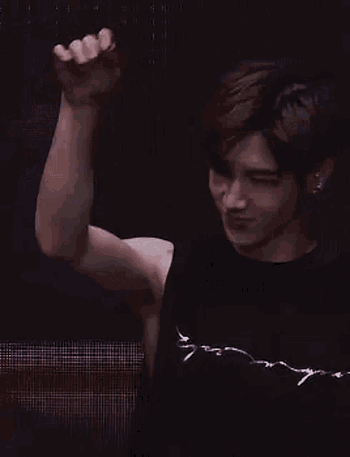 a man wearing a black tank top and ear buds is smiling .